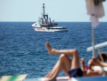 El vaixell de rescat 'Open Arms' davant les costes de Lampedusa (Itàlia) mentre uns turistes prenen el sol a l'illa.