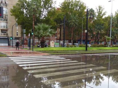 Una mujer cruza este viernes una avenida de Murcia. En vídeo, las imágenes del temporal esta madrugada.
