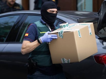 Un agente de la Guardia Civil se lleva material de uno de los domicilios registrados el lunes durante la Operación Judas. En vídeo, los detenidos prestarán declaración en la Audiencia Nacional.