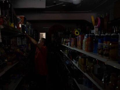 El dueño de una tienda en el centro de Santa Cruz coloca luces provisionales mientras espera que se restablezca el suministro eléctrico tras el apagón que ha afectado a toda la isla.