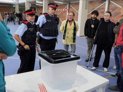 Dos 'mossos' ante una urna de un colegio durante la jornada del referéndum del 1 de octubre en Cataluña. En vídeo, las claves de la sentencia.