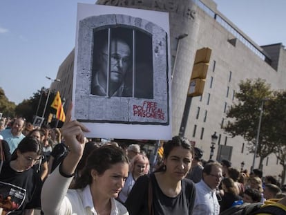 Una mujer sostiene una imagen de Raül Romeva en una concentración de simpatizantes independentistas ante la estación de Sants, en Barcelona. En vídeo, los altercados en el aeropuerto de El Prat.