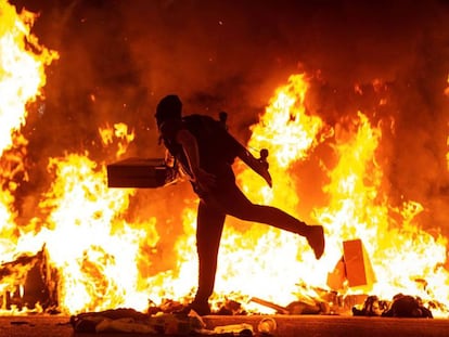 Un manifestante echa al fuego un cartón junto a la Delegación del Gobierno en Barcelona, durante los disturbios de esta noche.