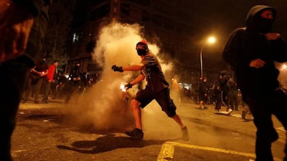 Un manifestante lanza un bote de humo durante los disturbios en Barcelona de este viernes. En vídeo, quinta jornada de disturbios.