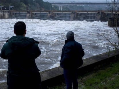 Dos hombres observan la fuerza del Miño a su paso por el embalse de Velle, en Ourense. En vídeo, los efectos de la borrasca Elsa en Galicia.