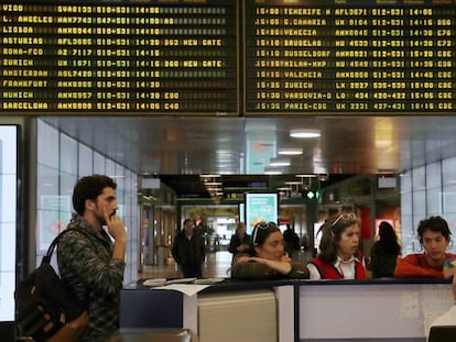 Varios pasajeros se informan sobre los vuelos retrasados y cancelados en Barajas, este lunes. En vídeo, Ignacio Rubio, presidente de Asetra, explica el procedimiento habitual en estos casos.