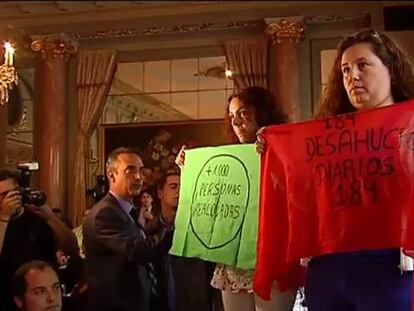 Dos miembros de la PAH despliegan pancartas en una conferencia de Cañete
