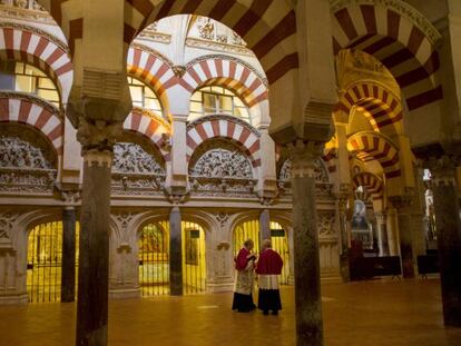 Dos sacerdotes conversan entre los arcos de la Mezquita de Córdoba.