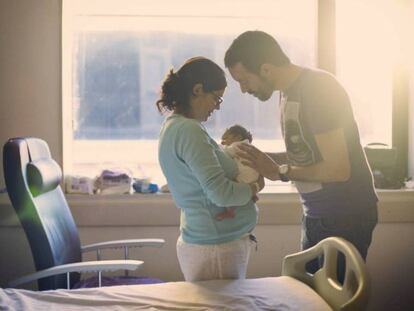 Una pareja mira a su recién nacido. En vídeo, declaraciones de la ministra de Hacienda.