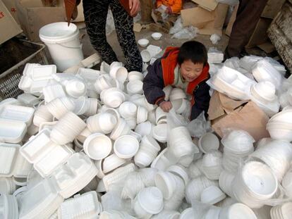 Un niño juega en Pekín con envases de comida a domicilio que serán destruidos por no cumplir estándares sanitarios.