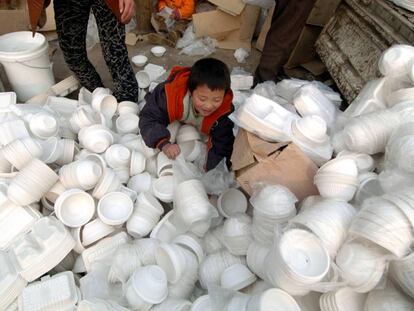 Un niño juega en Pekín con envases de comida a domicilio que serán destruidos por no cumplir estándares sanitarios.