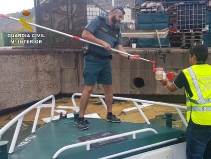 Dos agentes de la Guardia Civil recogen una muestra de agua.