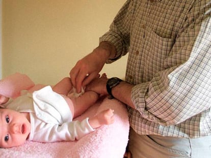 Un padre cambia el pañal a su bebé.