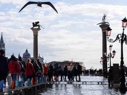 Varias personas caminan por la plaza de San Marcos de Venecia, completamente inundada.