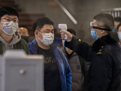 Controles para medir la temperatura en una estación de tren de Pekín. En vídeo, la OMS evita decretar la emergencia internacional por el virus de Wuhan.