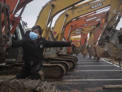 Un operario sube a una de las excavadoras que participan en la construcción de un nuevo hospital en Wuhan. En vídeo, la construcción del hospital.