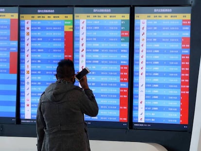 Un hombre mira los vuelos cancelados en un panel informativo del aeropuerto de Wuhan. En vídeo, tres españoles atrapados en Wuhan cuentan su día a día.