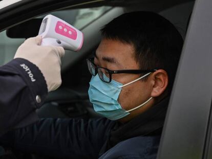 Un policía toma la temperatura a un hombre en Wuhan. En vídeo, el alcalde de la ciudad dice estar dispuesto a dimitir.