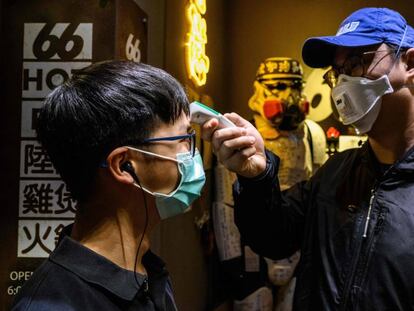 Un hombre le toma la temperatura a otro en Hong Kong. En vídeo, la OMS declara "enemigo público número uno" al coronavirus.