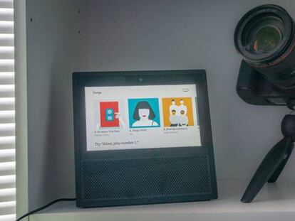Amazon Echo Show en una estantería junto a una cámara de fotos
