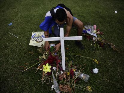 Un hombre deposita ofrendas en una cruz que simboliza las muertes.