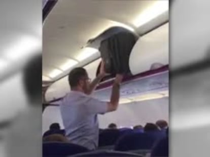 Un pasajero intenta meter su maleta en el compartimento de una cabina de avión.