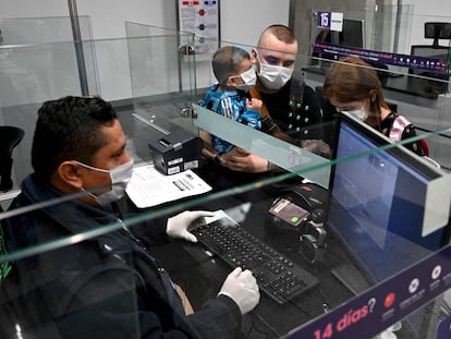 Viajeros con mascarillas en el aeropuerto de Bogotá. En vídeo, el anuncio del cierre de fronteras de los tres países.