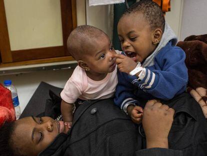 Una mujer juega con sus dos hijos en Lampedusa (Italia) tras ser rescatados en el Mediterr&aacute;neo, este jueves. 