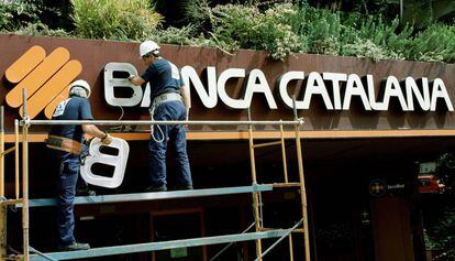 Operarios retiran el rótulo del banco, en el año 2000.