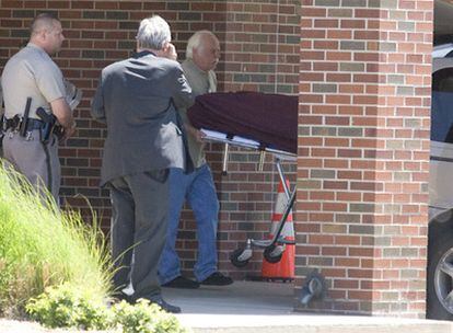 Agentes y personal forense retiran el cádaver del médico a las puertas de la iglesia donde fue tiroteado.