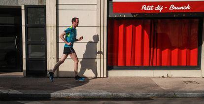 Un hombre corre cerca de un restaurante cerrado en París.
