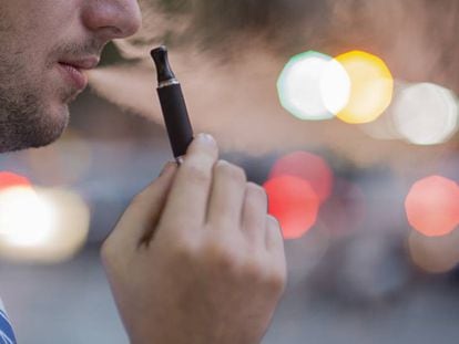 Un hombre fuma un cigarrillo electr&oacute;nico en una calle de Barcelona.