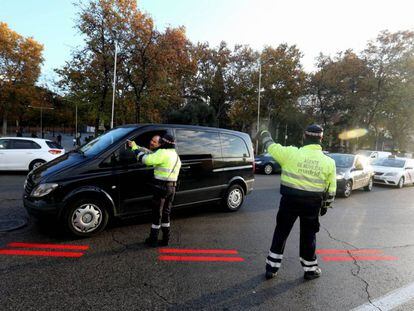 Dos agentes de Movilidad informan a un conductor sobre Madrid Central; en el suelo, la línea roja que delimita el área. 