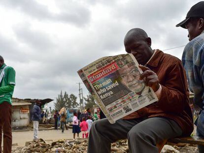 Dos hombres leyendo un periódico local con la portada dedicada a Koffi Annan.