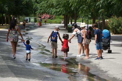 Varios niños, acompañados por adultos, pasean por un arroyo de agua en Valencia el pasado jueves.