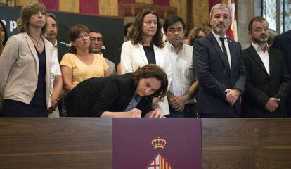 La alcaldesa de Barcelona, Ada Colau, acompañada de autoridades, firma en el libro de condolencias abierto en el Ayuntamiento.