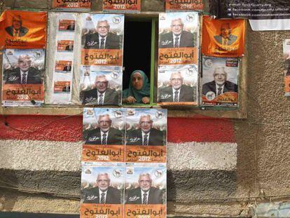 Una mujer asomada a una ventana rodeada de carteles del candidato Abulfut&uacute; en El Cairo. 