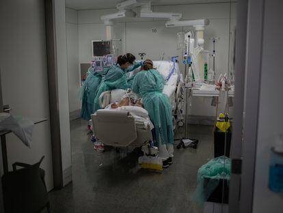 Sanitarias visitan a un enfermo en la UCI del Hospital de la Santa Creu i Sant Pau.