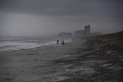 Varias personas en bicicleta en la playa de Atlantic Beach, Florida, a la llegada del huracán Matthew.