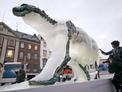 Los visitantes observan c&oacute;mo se derrite una escultura de un oso polar para mostrar un esqueleto de hierro. 