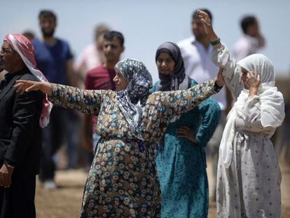 Diverses kurdes esperen els seus parents fugits de Kobane a la frontera.