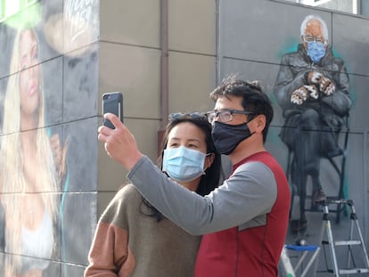 Dos personas se toman una foto junto a un mural del senador Bernie Sanders en Culver City, California.