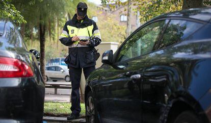 Un agent de la Guàrdia Urbana multa un vehícle estacionat en zona blava a Barcelona.