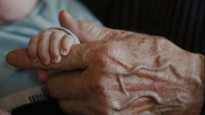 Un bebé agarra la mano de su abuelo.