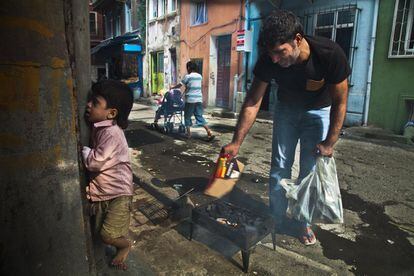 Una familia kurda prepara una pequeña brasa para hacer carne asada en la calle.
