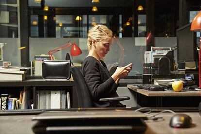 Una mujer consulta su teléfono en el trabajo.