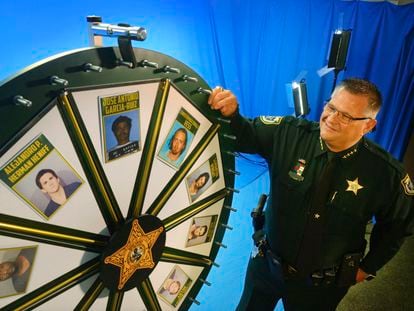 El sheriff Wayne Ivey posa junto a su 'Rueda de fugitivos' en Titusville, Florida, en 2017