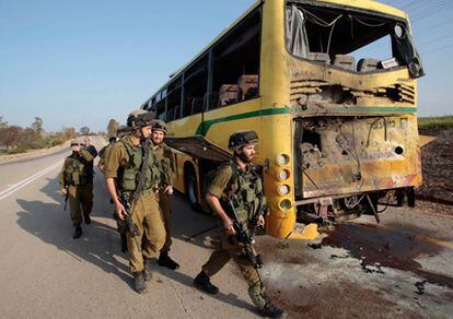 Soldados israelíes pasan junto a un autobús contra el que impactó un proyectil de mortero disparado desde la Franja de Gaza hacia el sur de Israel, en la carretera entre Kibbutz de Nahal Oz y kibutz Saad.