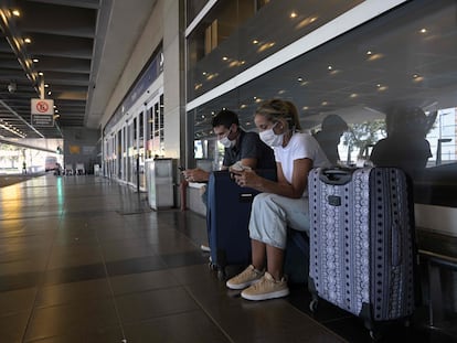 Una pareja usa sus móviles frente a las puertas de ingreso del aeropuerto de vuelos domésticos  Jorge Newbery, en Buenos Aires, el pasado 20 de marzo.