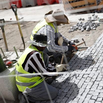 Dos obreros de la construcción pavimentan la acera en la calle Alcalá, este lunes en Madrid. 